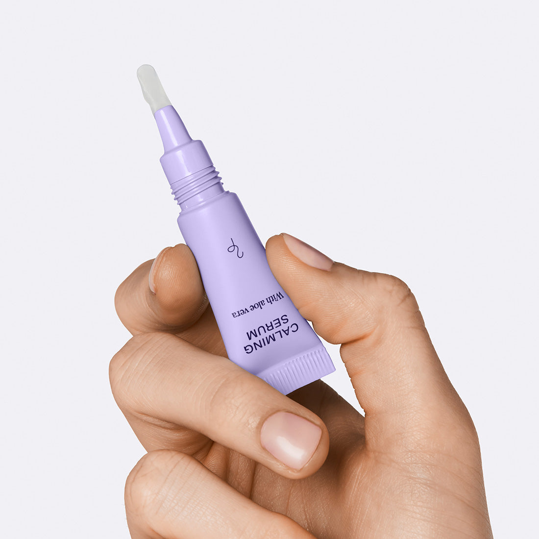 Hand holding the Flamingo Calming Serum showing the small plastic tip applicator